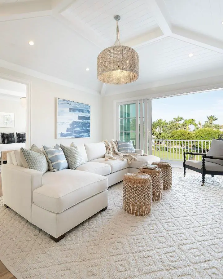 Neutral sectional with woven pendant light from @calusabaydesign. Beachy living space with ocean artwork and natural textures.