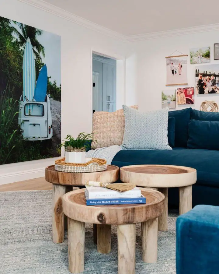 Natural wood coffee tables from @tamrablair_interiordesign showcasing coastal living room ideas with navy sectional and tropical artwork.