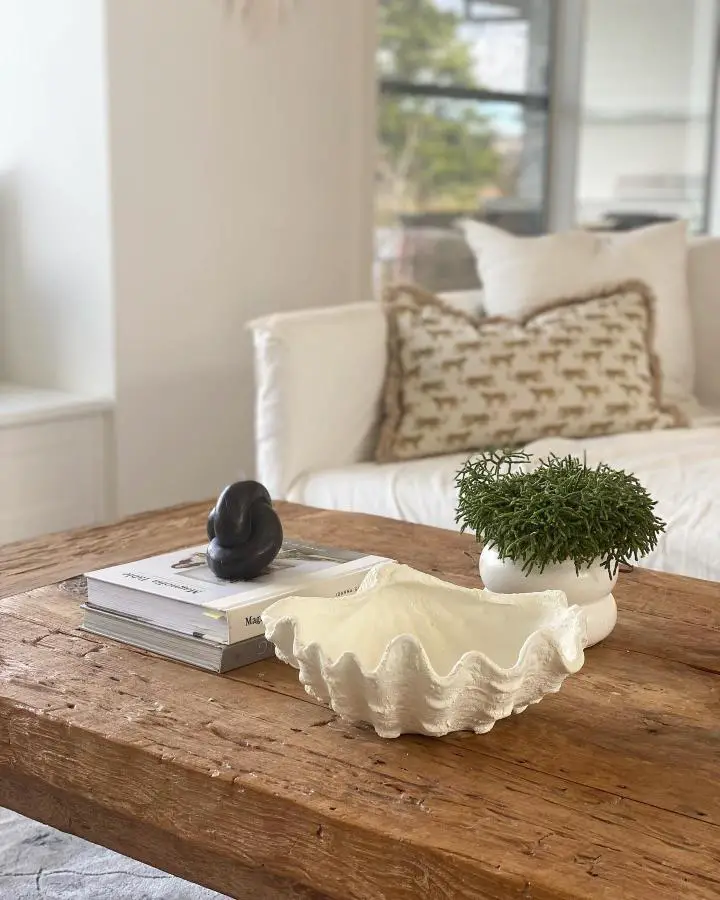 Oversized cream clam shell bowl on weathered wood coffee table from @you.me.and.the.sea_. Natural texture and beachy vibes.