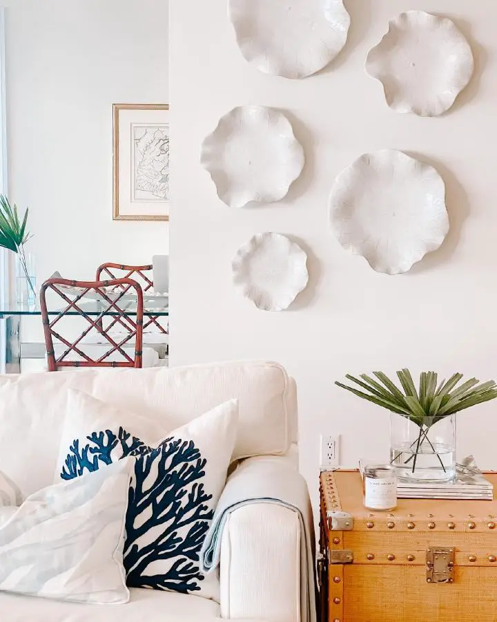 White sculptural coral wall art from @vondergoltz_assalidesignstudio. Textured ceramic pieces mounted above cream sofa.