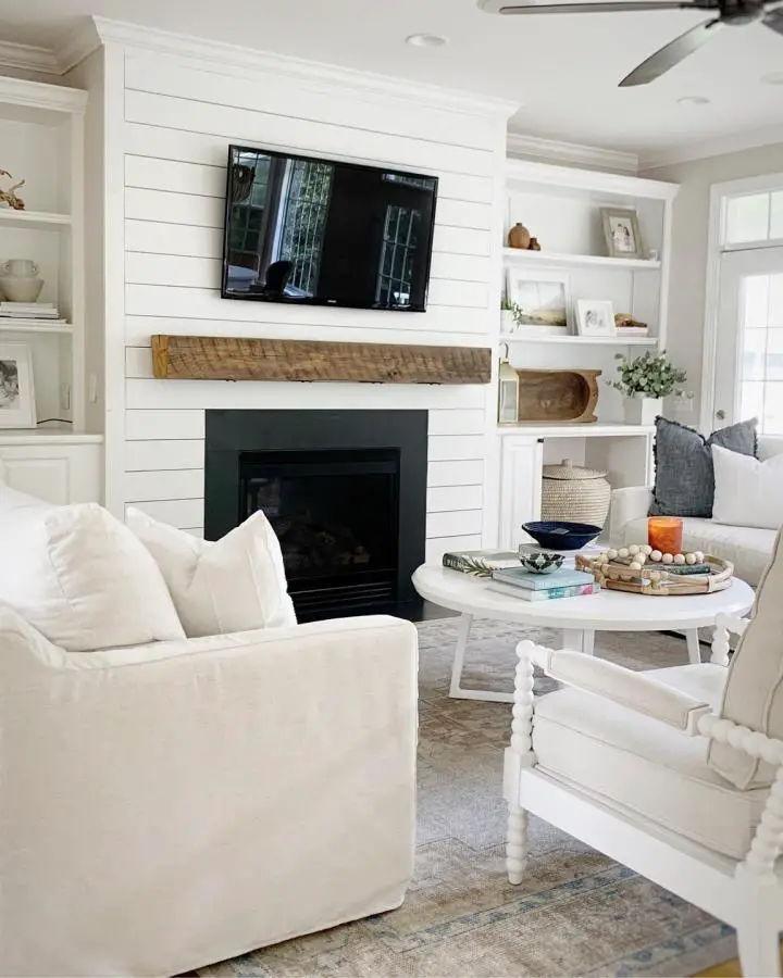 White shiplap fireplace wall from @thecoastaloak. Built-in shelving displays coastal accessories and books perfectly.
