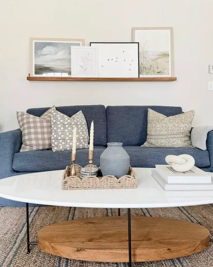 Navy sectional sofa with neutral pillows showcasing coastal living room ideas from @debpresutto_art. Mixed textures and calming color palette.