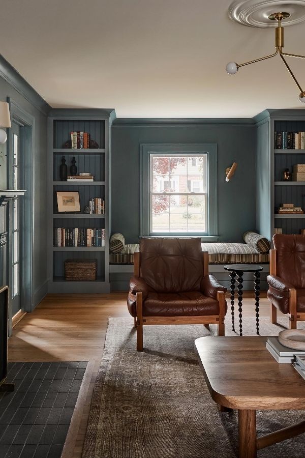 Elegant colonial living room with ornate fireplace, bookshelves, and vintage furnishings.