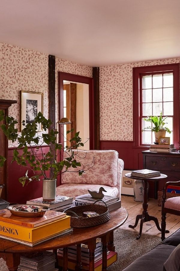 Colonial living room with floral wallpaper, cozy furniture, and fireplace.