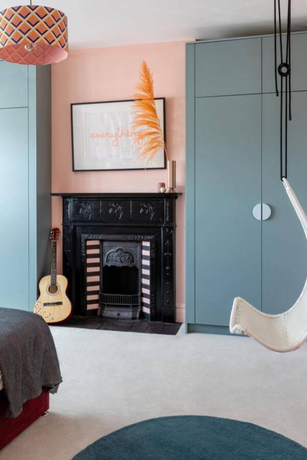 Vintage fireplace adds charming character to cozy bedroom with colorful, eclectic decor from @em.gurner.