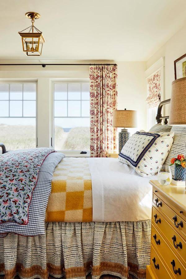 Layered floral and gingham bedding from @katierosenfeld. Cozy patterns embrace the cottagecore aesthetic.