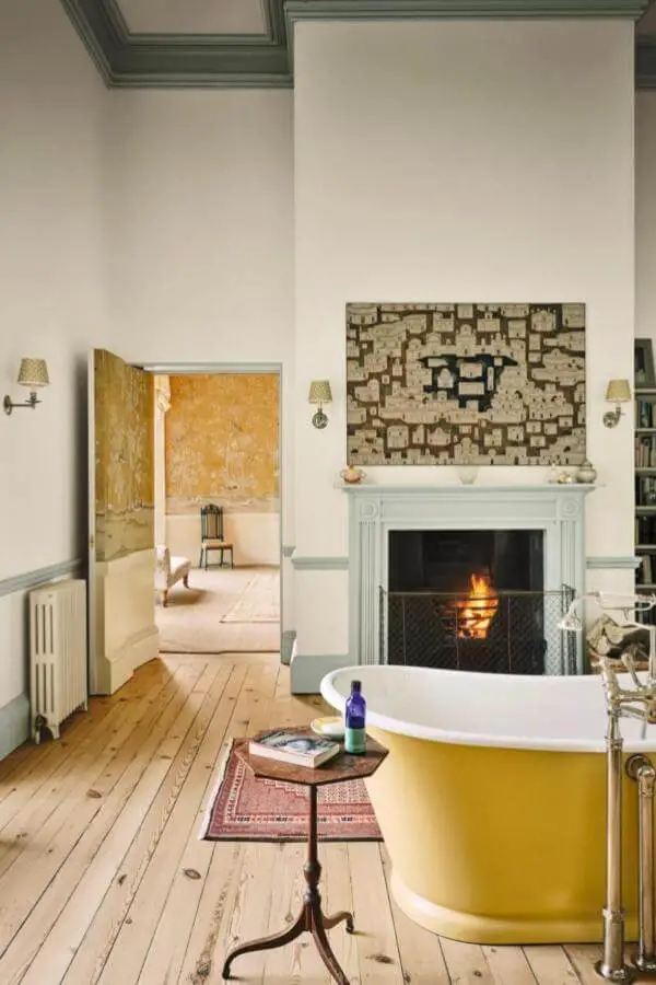 Mustard yellow clawfoot bathtub from @horwoodphoto. Rustic wooden floors and working fireplace create cozy farmhouse atmosphere.