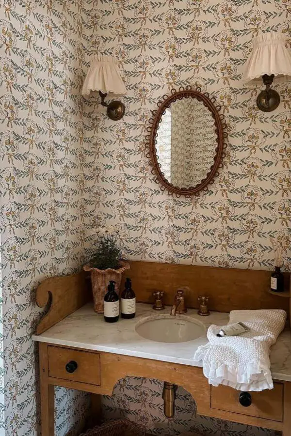 Botanical wallpaper bathroom from @faegerandco. Wood vanity with brass fixtures and wicker accessories.