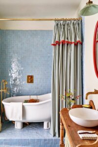 Black and white striped shower curtain from @lonikachande showing cottagecore bathroom ideas with red trim detailing.