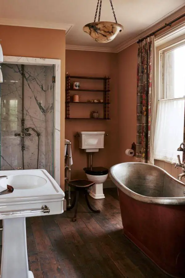Copper freestanding bathtub from @max_rollitt. Terracotta walls and vintage fixtures complete the rustic aesthetic.