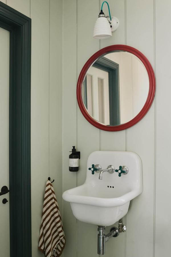 Red framed round mirror from @emma__ainscough showcasing perfect cottagecore bathroom ideas with vintage white sink.