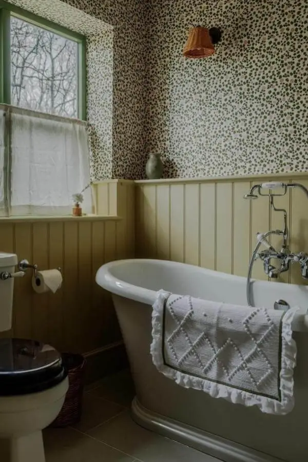 Spotted wallpaper bathroom from @astrid_houssin. Green wainscoting and vintage clawfoot tub create rustic charm.