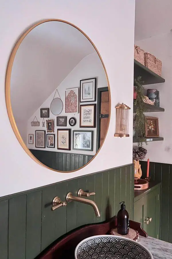 Vintage framed artwork gallery wall from @thatstonecottage. Features mixed frames above green wainscoting with brass mirror.