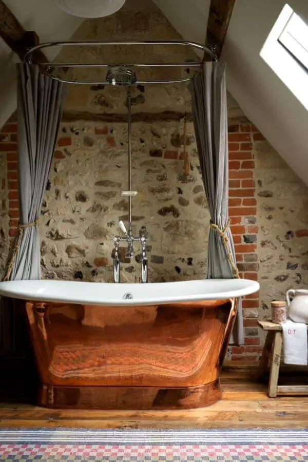 Copper clawfoot bathtub from @simonbrownphotography. Rustic stone walls and vintage curtain rail complete the look.