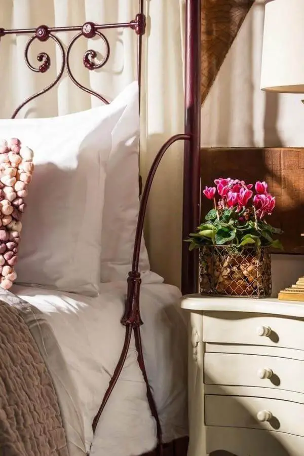 Black wrought iron bedframe from @undercastlecottage. Delicate floral accents create cozy cottagecore bedroom charm.