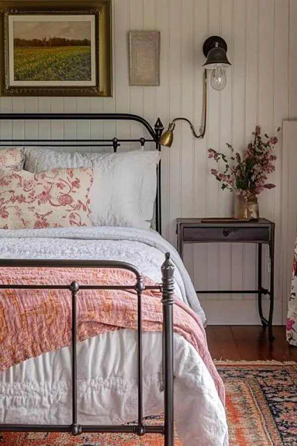 White vintage iron bedframe from @townandcountryliving. Anchors this cozy cottage retreat with classic cottagecore charm.