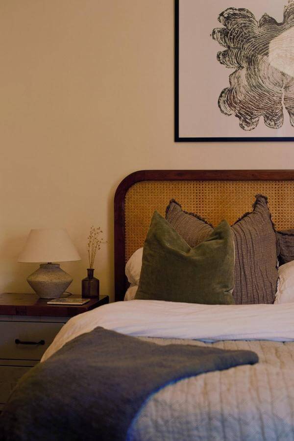 Warm-toned classic cane headboard from @serene_sarah_. Cozy charm highlights this inviting cottagecore bedroom.