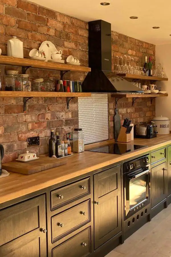 Rustic brick wall kitchen from @theolivebranchkitchens. Open wooden shelving displays vintage dishes and glass storage jars.