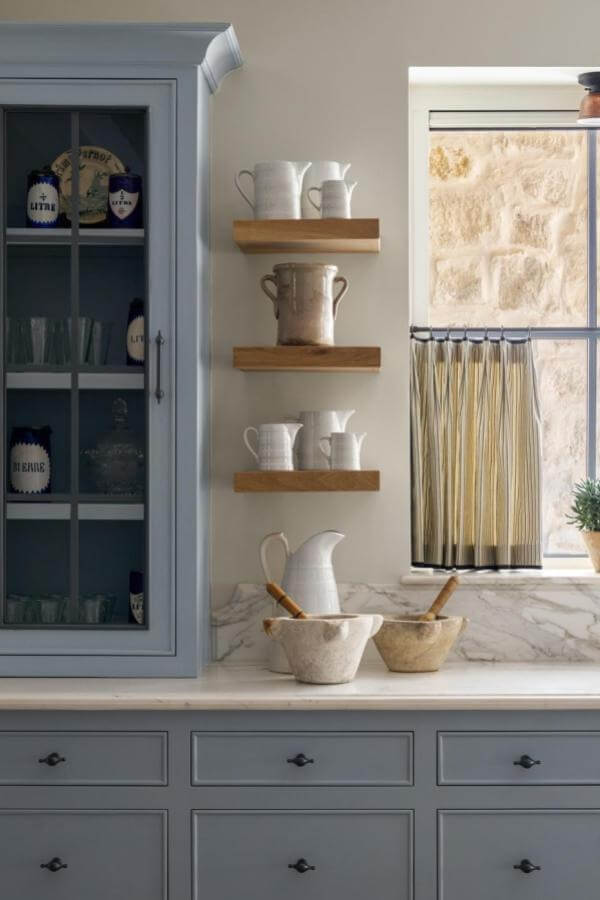 Rustic floating shelves from @kristinmullendesigns displaying white ceramics and vintage stoneware pieces.