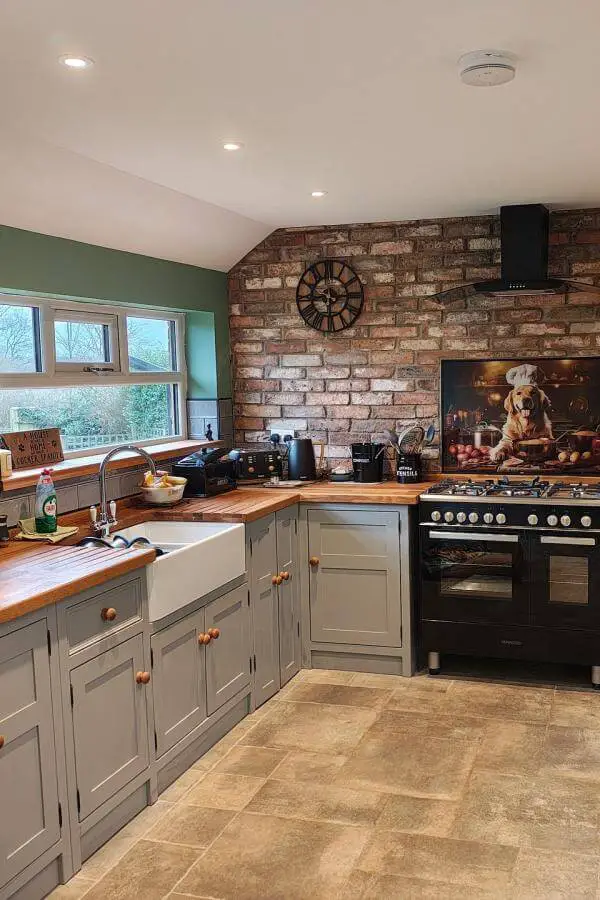 Rustic brick accent wall kitchen from @theolivebranchkitchens. Natural textures and sage green cabinets create farmhouse warmth.