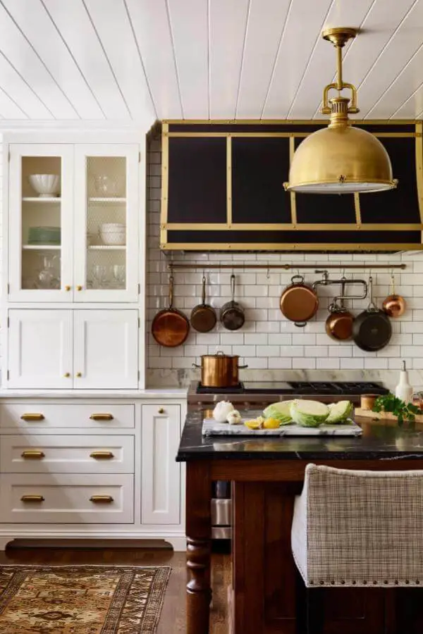 Oversized brass dome pendant light from @katierosenfeld. Hangs above dark wood kitchen island with copper cookware display.