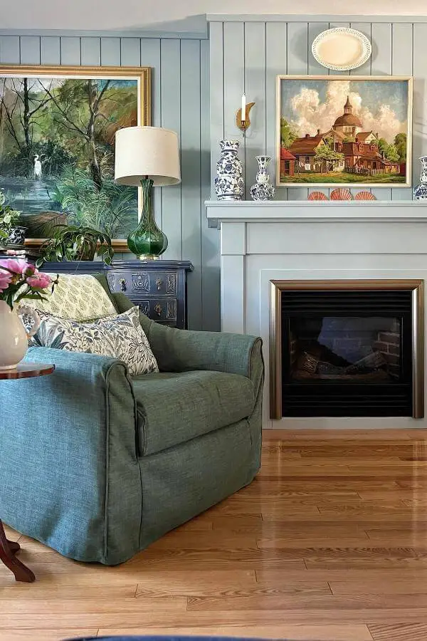 Layered vintage paintings in warm tones above wooden mantel from @jogalbraithathome. Showcases rustic depth and texture.