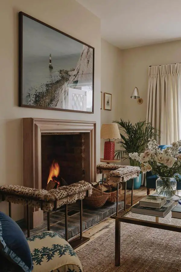 Cozy rustic fireplace with plush patterned stools from @emma__ainscough. Chic cottagecore living room inspiration.