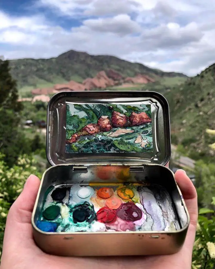 Miniature watercolor painting kit from @heidilooart with landscape art and colorful paint wells in repurposed tin.