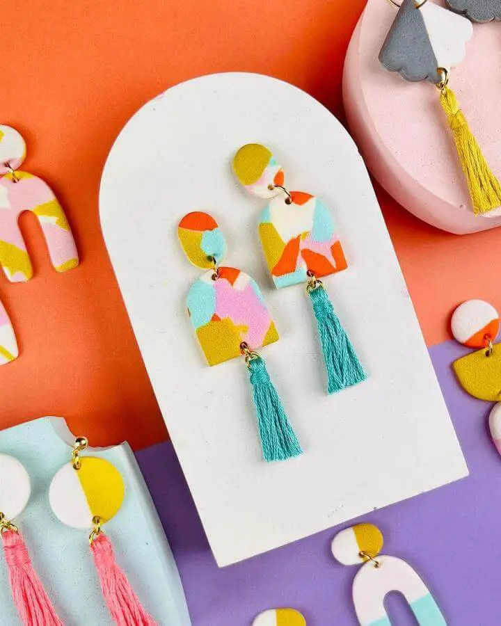 Colorful polymer clay earrings from @theedinburghcraftclub. Geometric shapes with turquoise tassels displayed on white card.