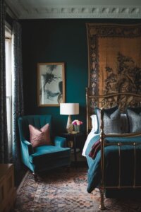 Vintage-inspired bedroom with brass bedframe, floral wallpaper, and cozy atmosphere.
