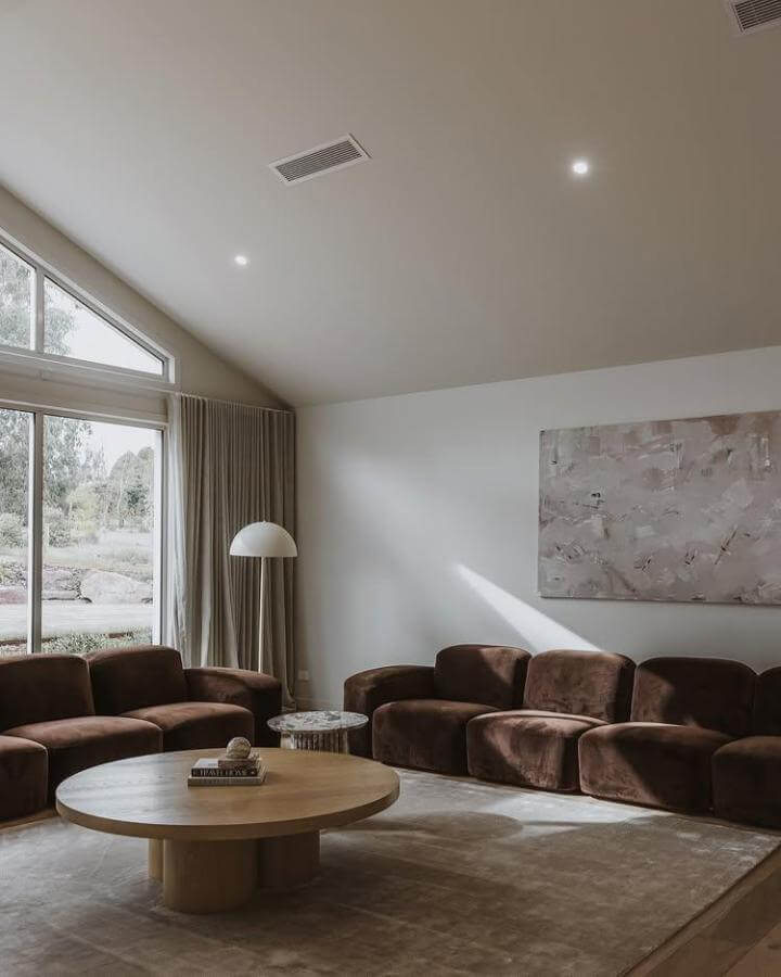 Dark brown velvet couches with rounded edges in a minimalist living room by @roseleigh_homes featuring natural wood and neutral tones.