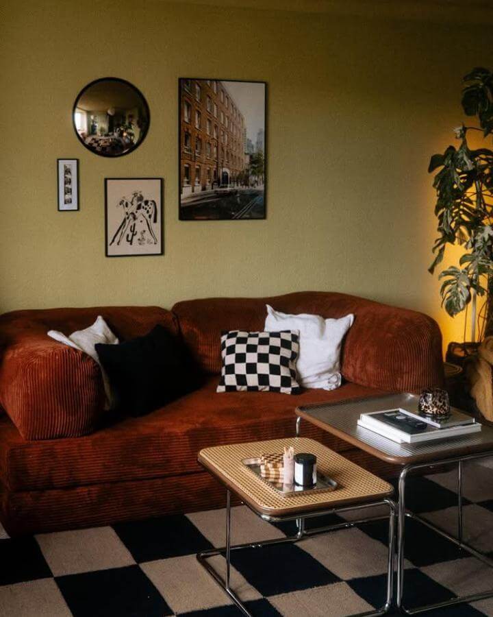 Dark brown corduroy sofa with checkerboard pillow and rug in cozy living room by @trixedenbreuls, warm inviting space.
