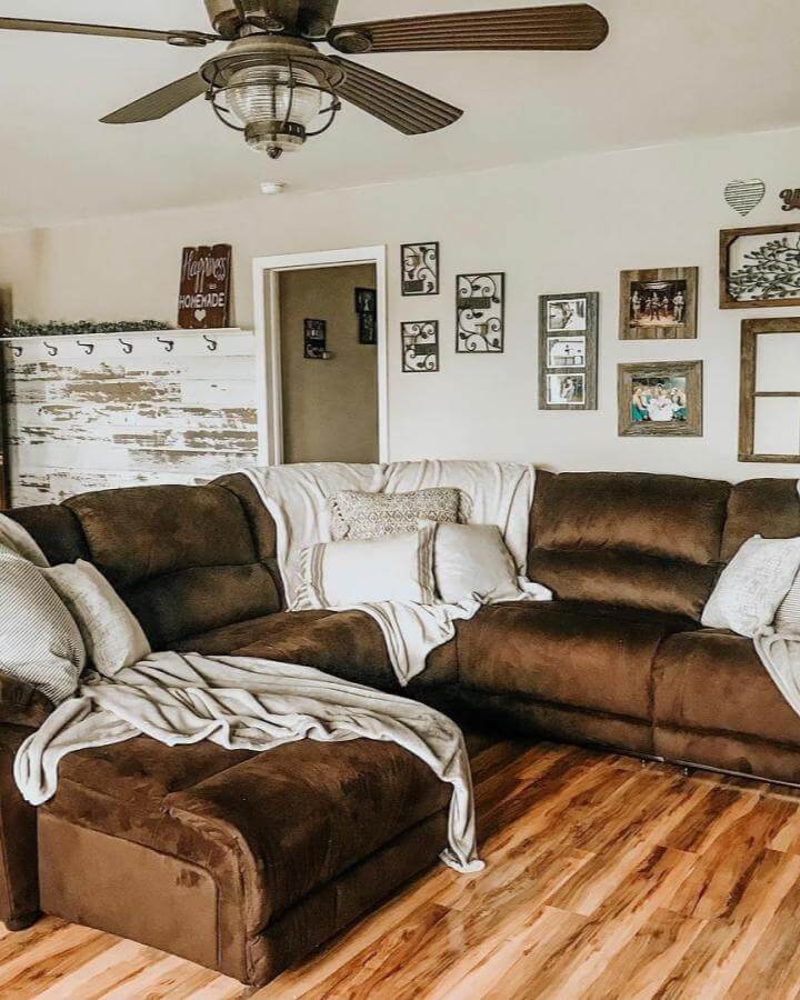 Dark brown plush sectional in cozy rustic farmhouse living room with wood flooring and neutral pillows from @fauxfarmhouseranch.