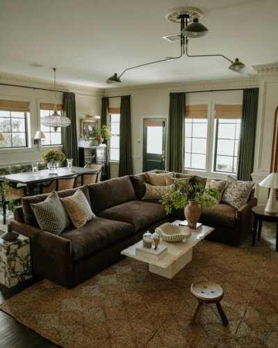 Dark brown velvet couch with layered cushions and jute rug in a warm, inviting living room by @arceriinteriors.