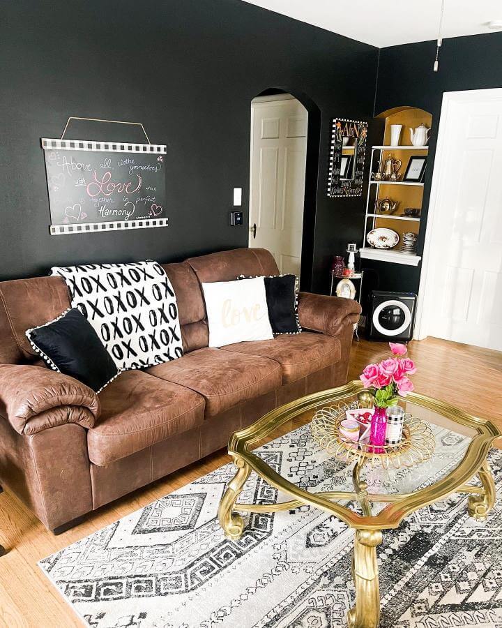 Dark brown suede couch with black walls and gold coffee table from @thissplendidstruggle showcasing cozy, stylish living room contrast.