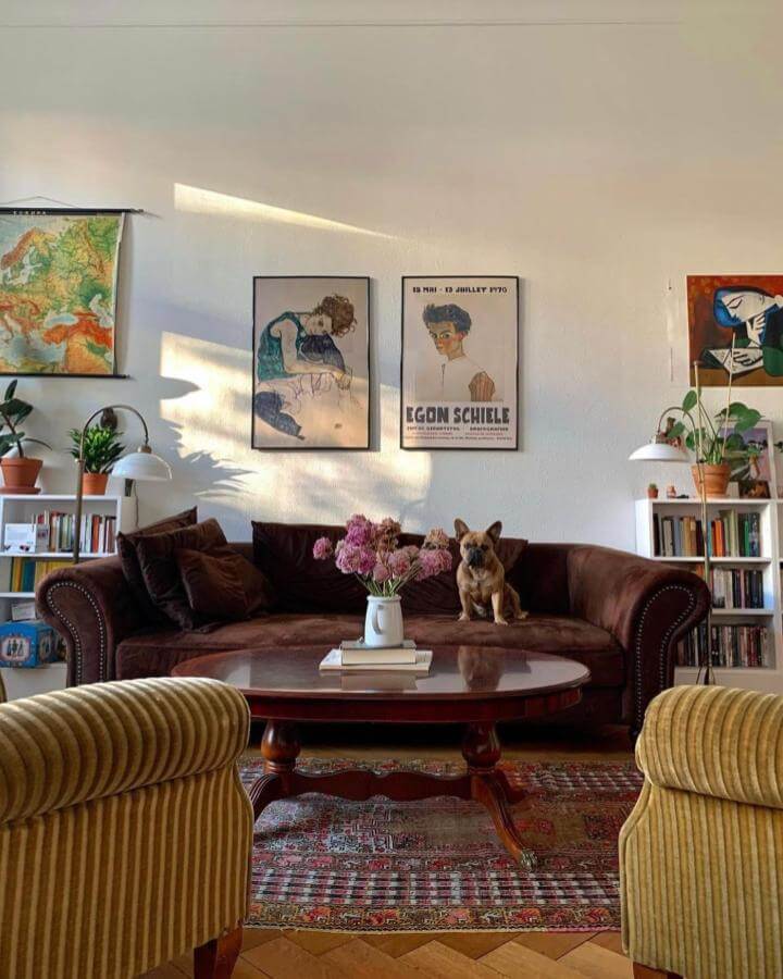 Dark brown velvet couch with vintage wood coffee table and mustard corduroy chairs in cozy eclectic living room from @maximalist.decorating.