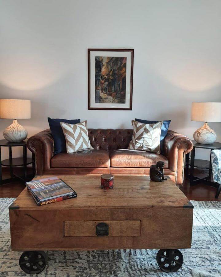 Dark brown leather Chesterfield couch with patterned pillows and wooden coffee table in cozy living room from @totalhomeworxdxb showing stylish dark brown couch living room ideas.