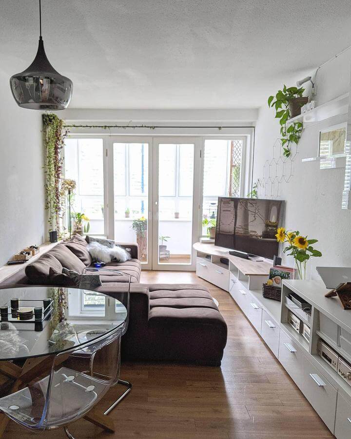 Dark brown sectional couch living room ideas with wood flooring, transparent chairs, and green plants by @nidelmary creating cozy, stylish space.