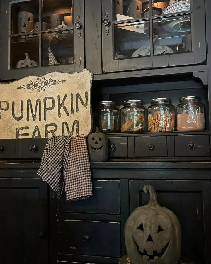 Black painted hutch from @shady_pines3interiors. Mason jars and pumpkin decor create autumn storage display.