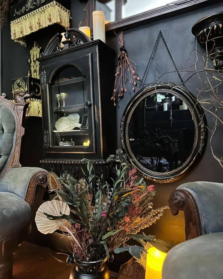 Ornate black Victorian display cabinet from @immortal_curio_company. Gothic styling with autumn florals and mysterious collectibles.