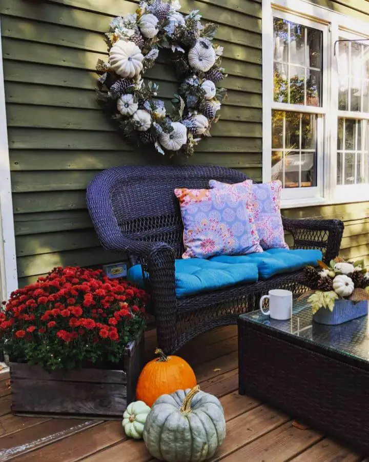 Neutral fall wreath with fabric pumpkins from @mynhhome. Cream and gray pumpkins with dusty miller on dark wicker furniture.