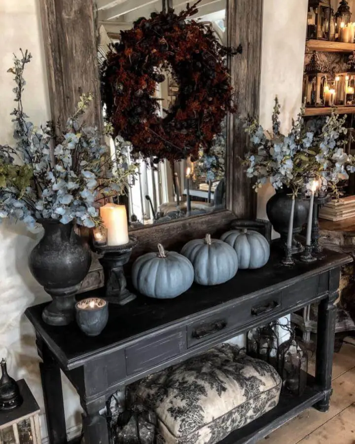 Sage green pumpkins arranged on dark console table showcasing sophisticated dark fall decor ideas with eucalyptus and candles