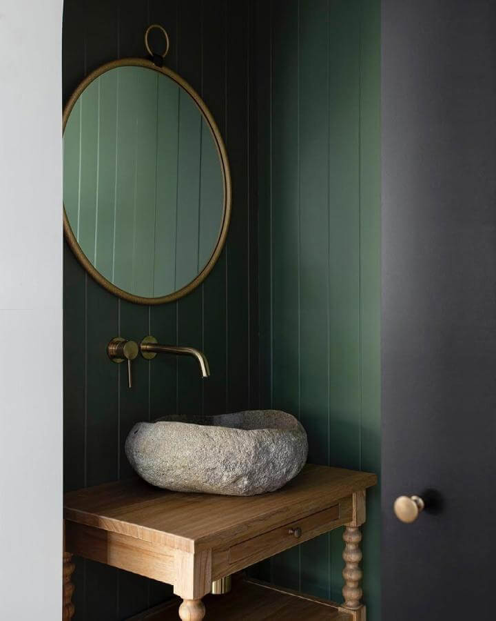 Dark green powder room with stone vessel sink, natural wood vanity and brass fixtures by @carleneduffystudio creating rustic modern style.