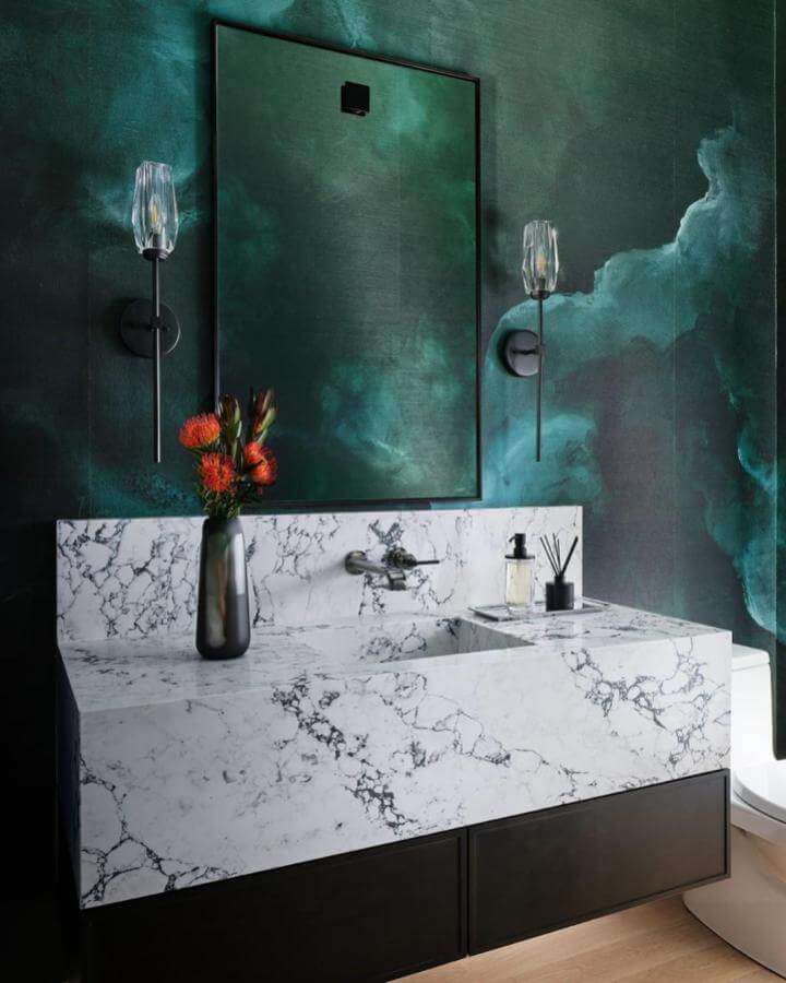 Dark green powder room with marble sink and black vanity by @dustinforest glowing under glass sconces.