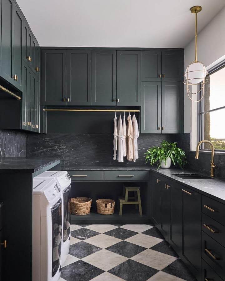 Matte black cabinetry laundry room with brass accents and checkered marble tile floor from @angelineandcointeriors modern and elegant space.