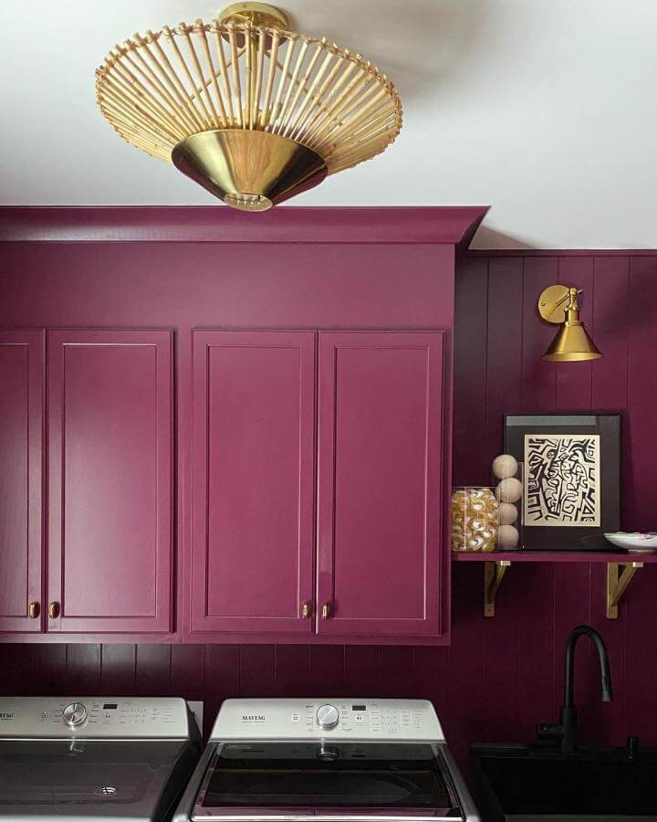 Plum cabinetry with brass fixtures and black sink laundry room design by @abbymanchesky showing moody, stylish, functional space.