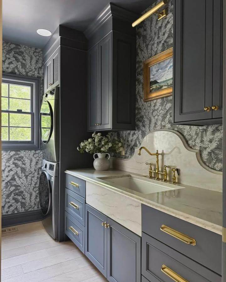 Dark charcoal cabinetry with brass hardware and floral wallpaper in a stylish dark laundry room ideas setup by @blushingboho. Elegant and inviting design.