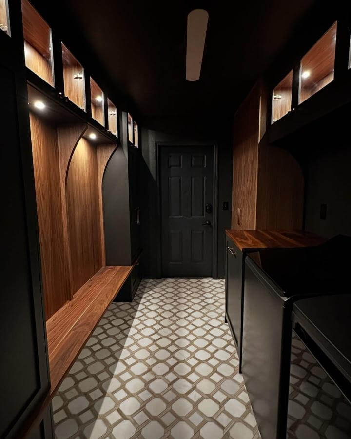 Dark matte black laundry room with warm wood cabinetry and patterned tile floor inspired by @tillertradeco project showcasing cozy modern design.