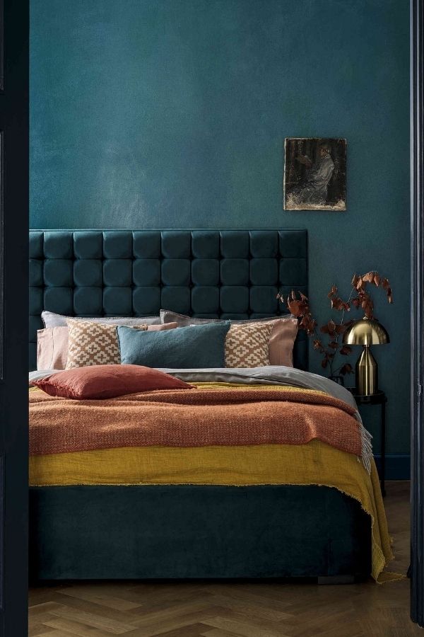 A teal room with cozy textiles, elegant decor, and warm lighting.