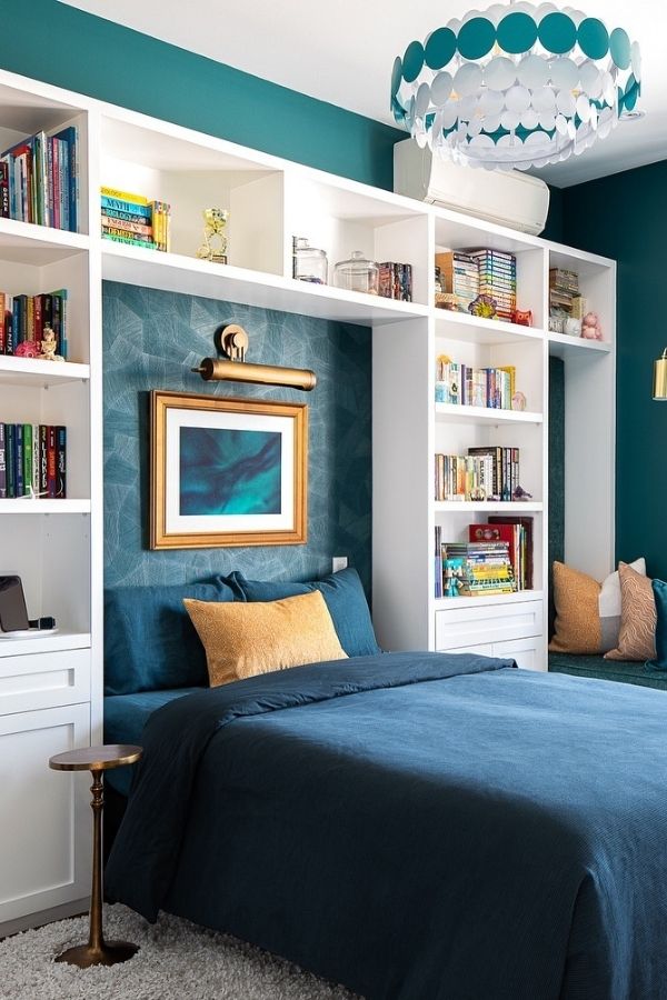 A cozy nook with teal accents, bookshelves, chair, and plants.